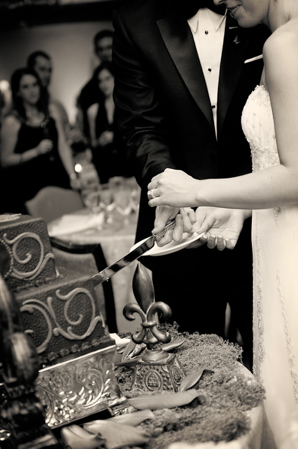 Black and white photo - The bride and groom cutting cake at the reception -photo by Houston based wedding photographer Adam Nyholt
